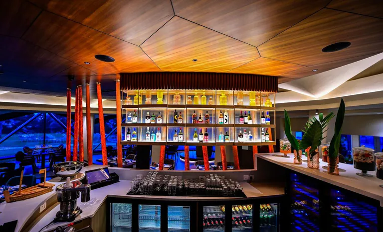 Modern, well-stocked bar with illuminated shelves and stylish wooden ceiling at The Park Visakhapatnam.